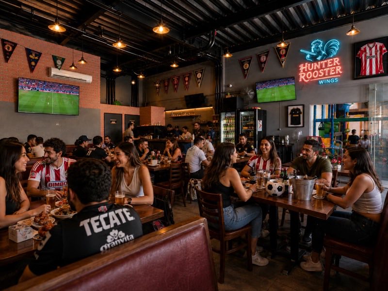 Interior de un Hunter Rooster con pantallas de futbol y muro de jerseys